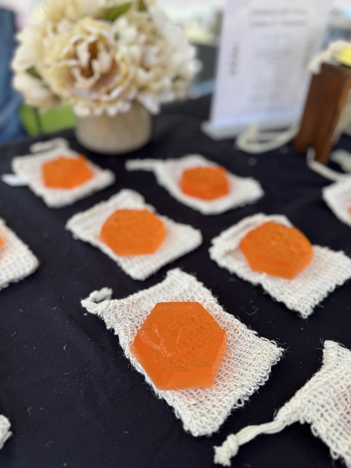 Orange hexagonal soaps embossed with a honeycomb and bee on crocheted pouches