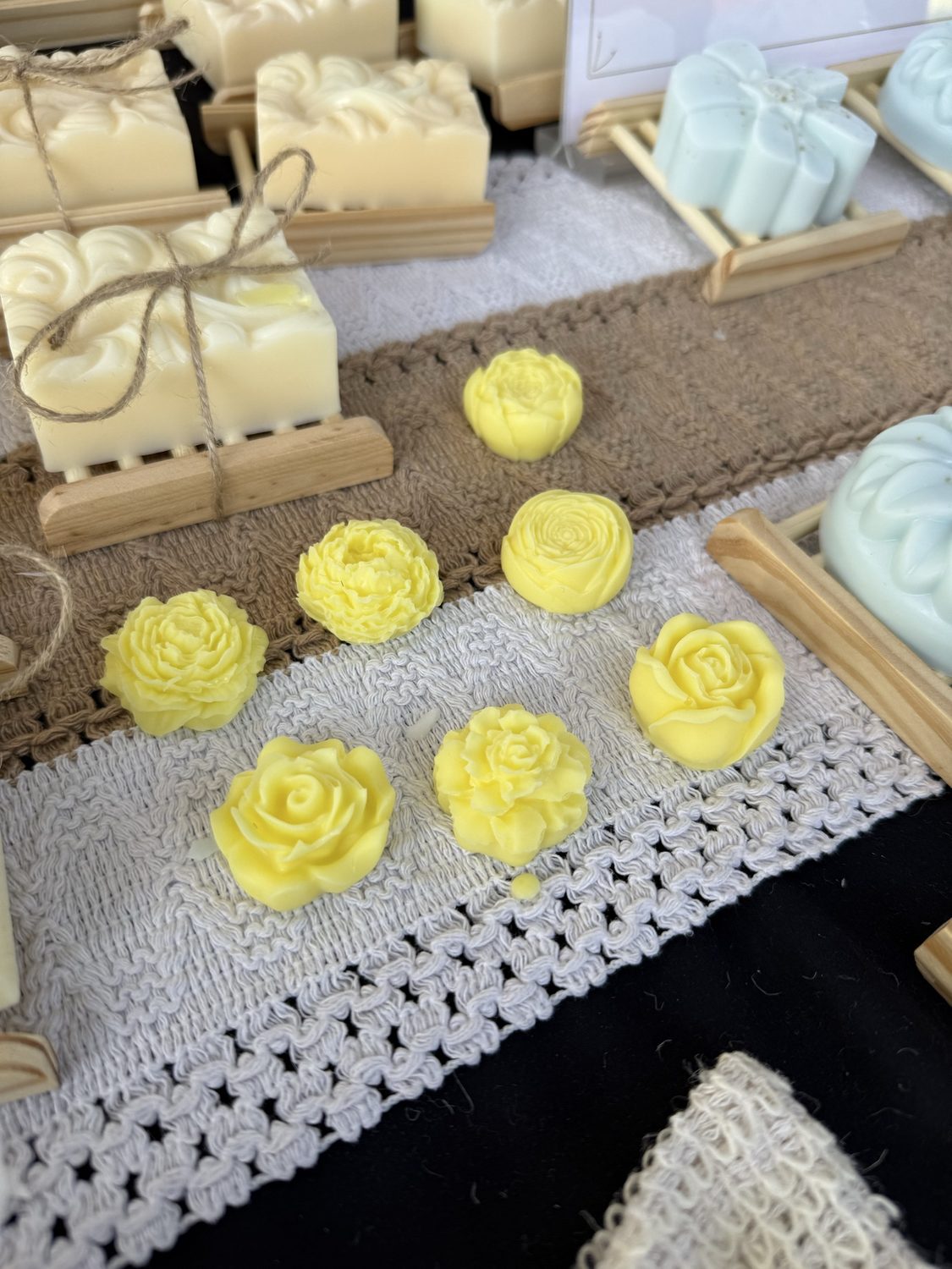 Small yellow soaps molded into rose and peony flower shapes on lace